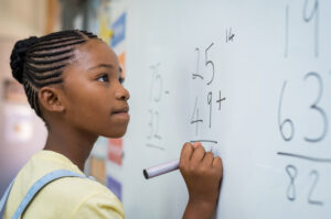 pupil doing a math equation on the whiteboard